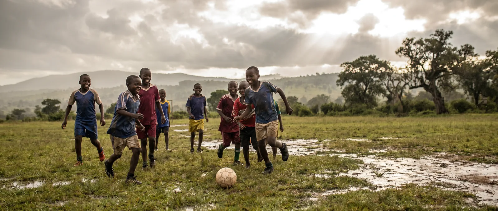 Kinder spielen Fußball unter wechselhaftem Himmel